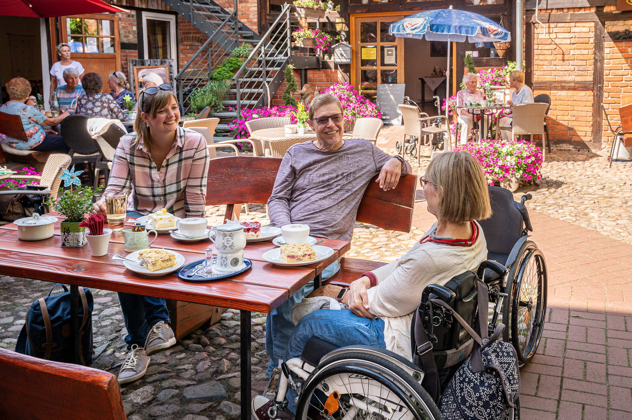 Eine Gruppe Urlauber beim Kaffeetrinken auf der Terrasse in einem Hofcafé in Bad Bevensen