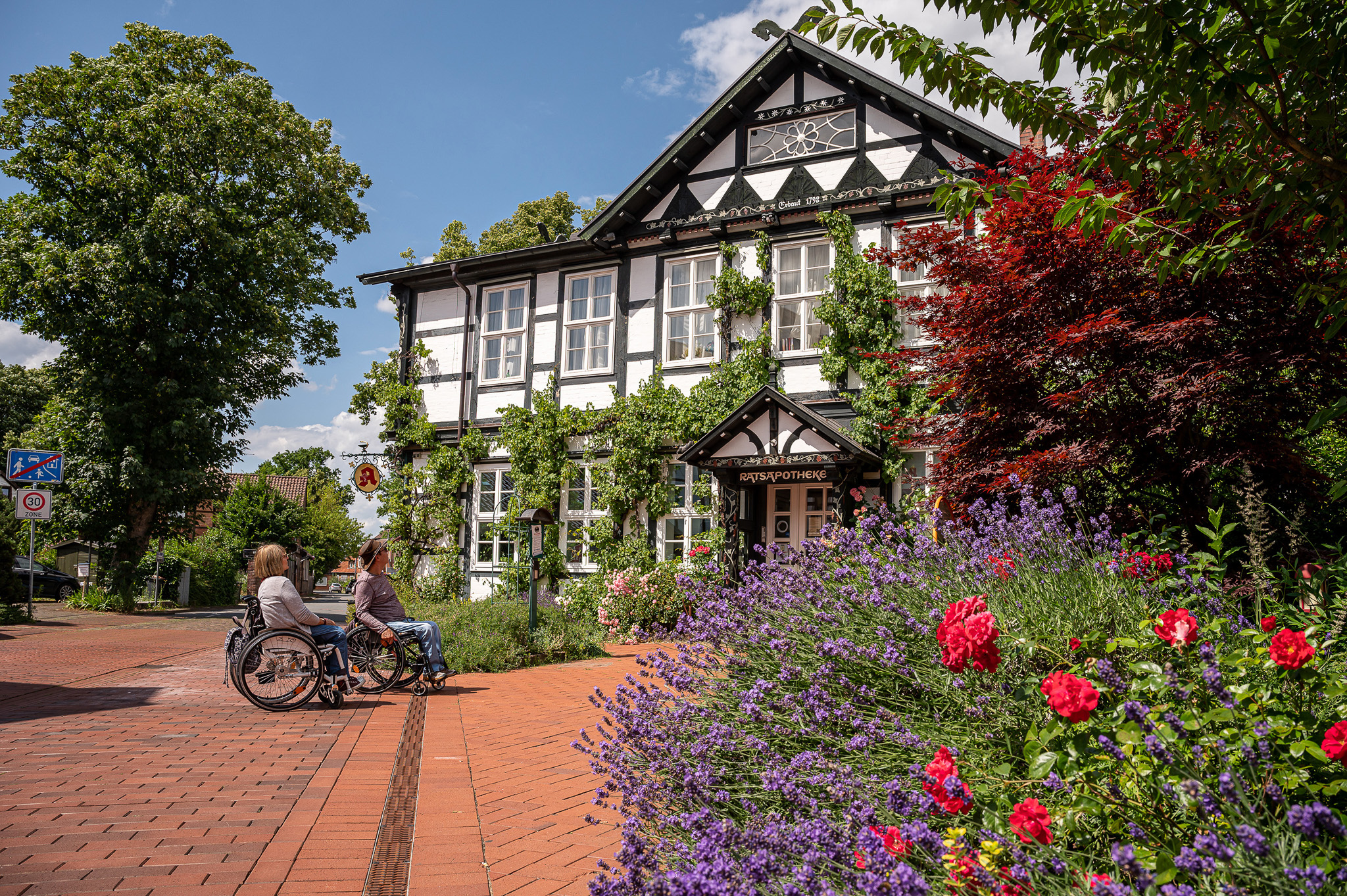 Urlauber im Rollstuhl betrachten die Ratsapotheke Bad Bevensen